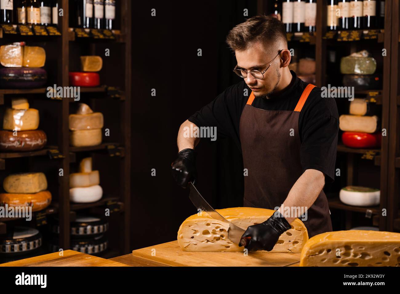 Limited maasdam cheese wheel cutting cheese in store. Cheese sommelier