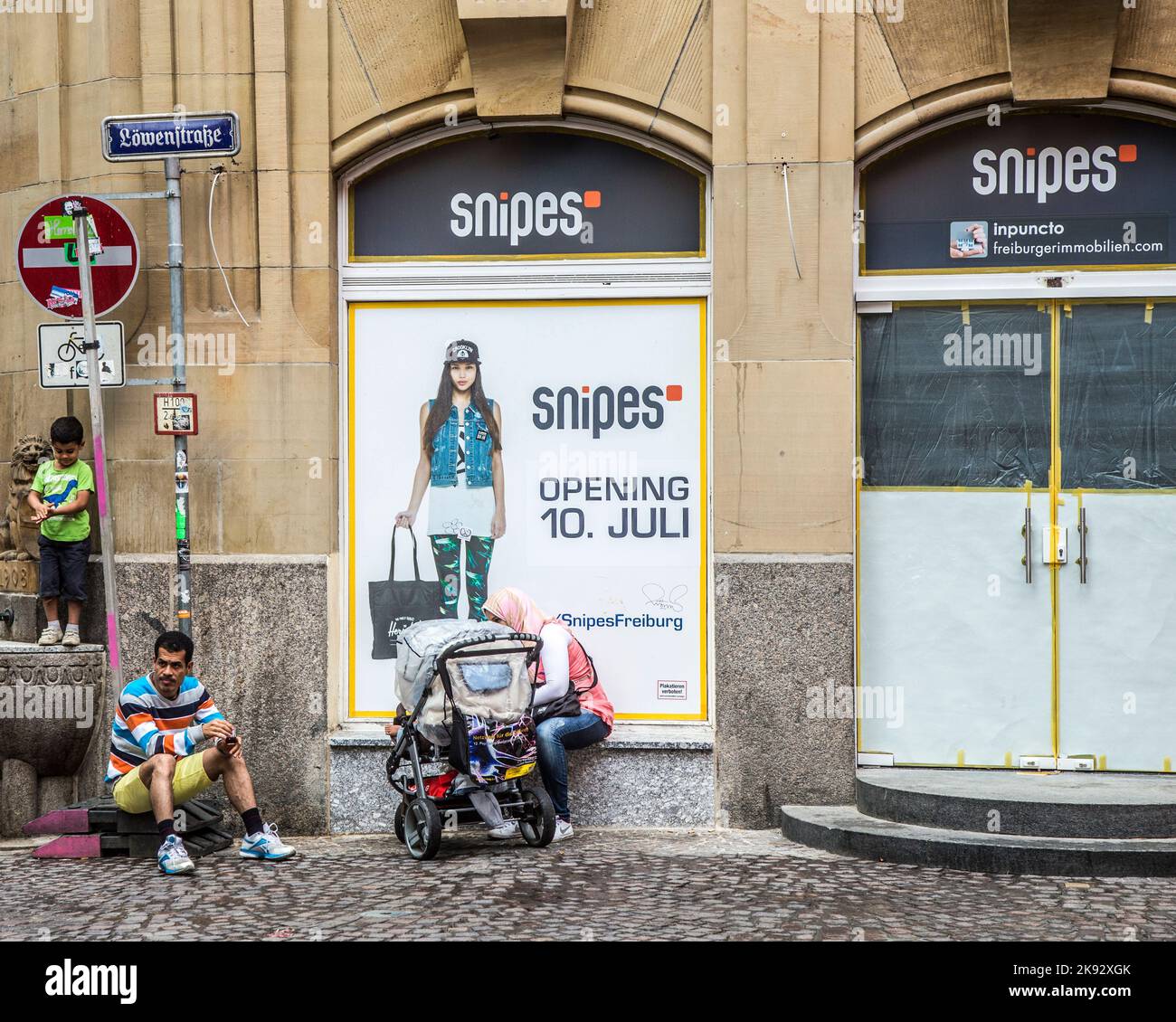 FREIBURG, GERMANY - JULY 29, 2014: turkish family rests at the entrance of an old house in Freiburg, Germany. famous old bus transports people to tour Stock Photo