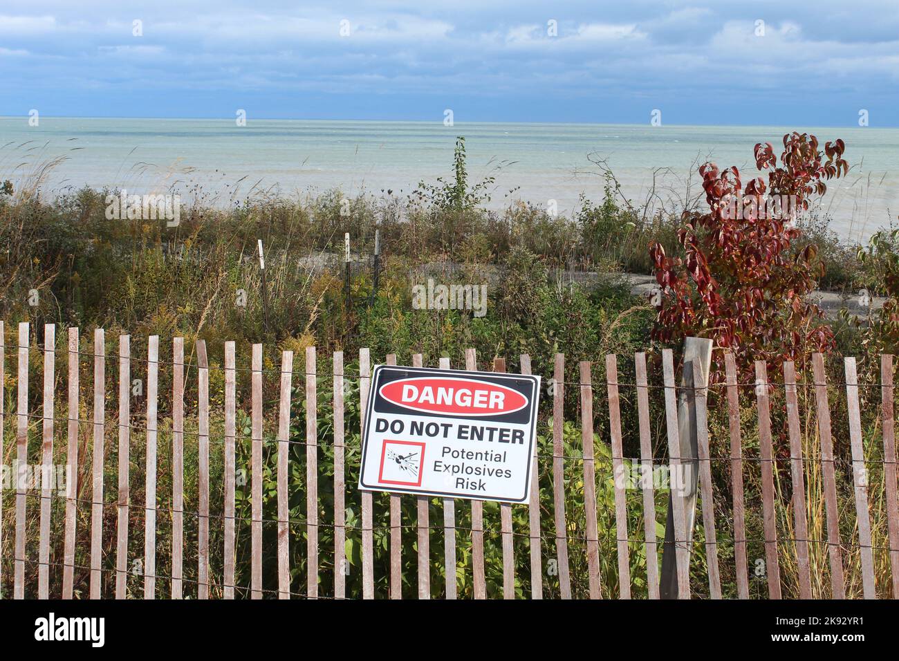 Danger Do Not Enter Potential Explosives Risk sign on a snow fence in autumn with Lake Michigan in the background at Fort Sheridan, Illinois Stock Photo