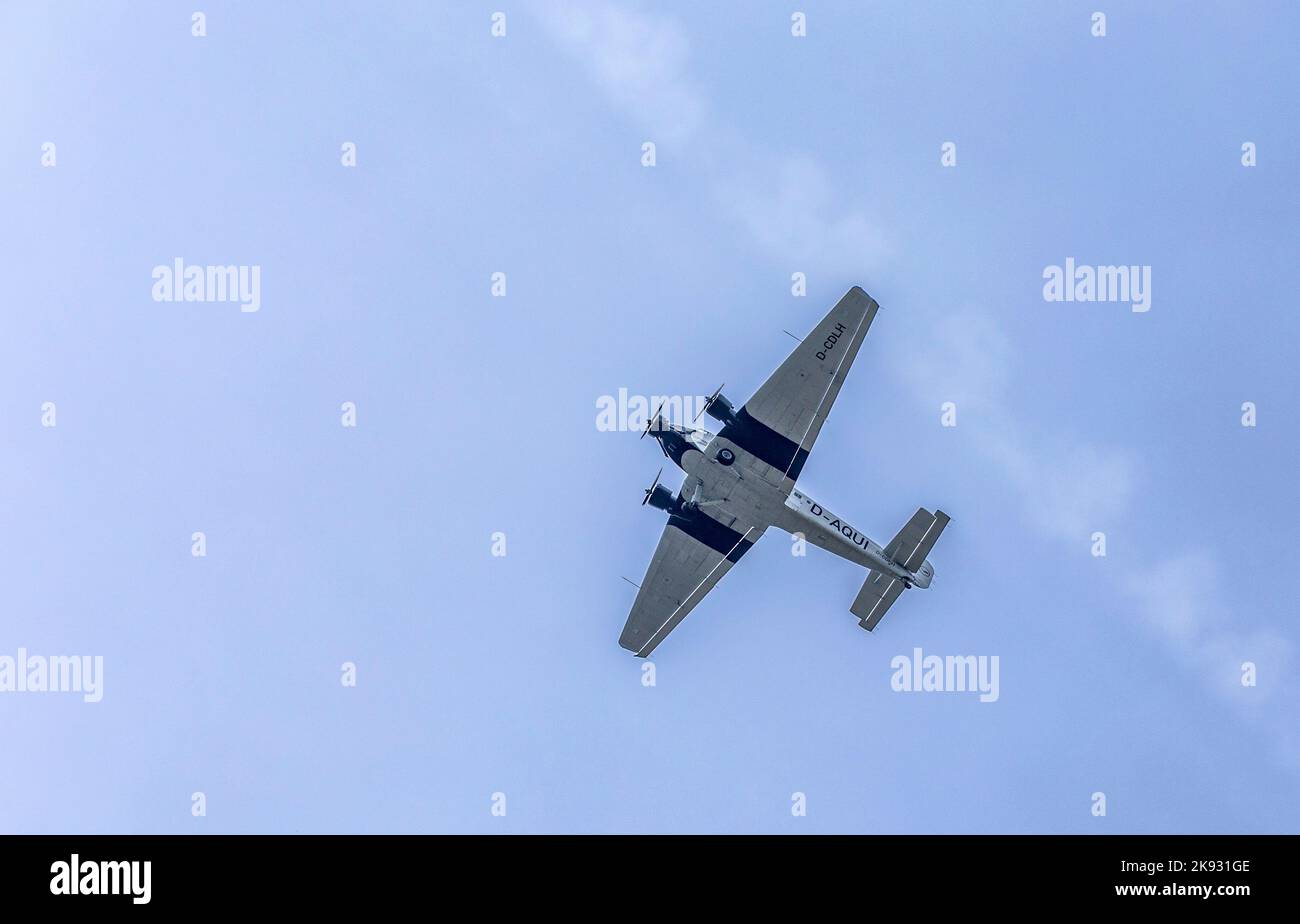 SCHWALBACH, GERMANY - MAY 31, 2015: Junkers Ju52 D-AQUI  flights over the Taunus region at cloudy sky in Schwalbach, Germany. The flight is bookable b Stock Photo
