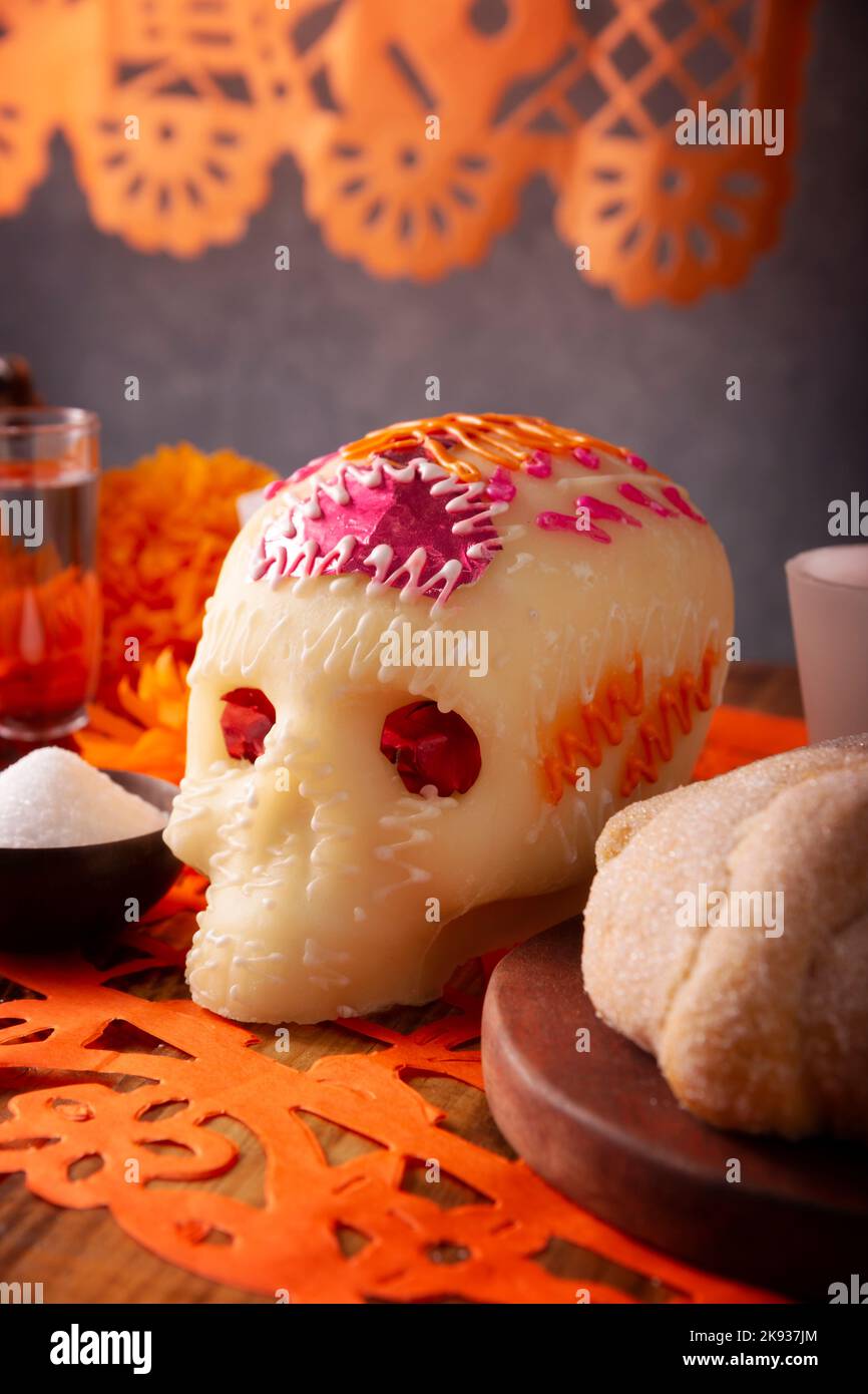Sugar skull with Pan de Muerto and Papel Picado. Decoration traditionally used in altars for the celebration of the day of the dead in Mexico. Stock Photo