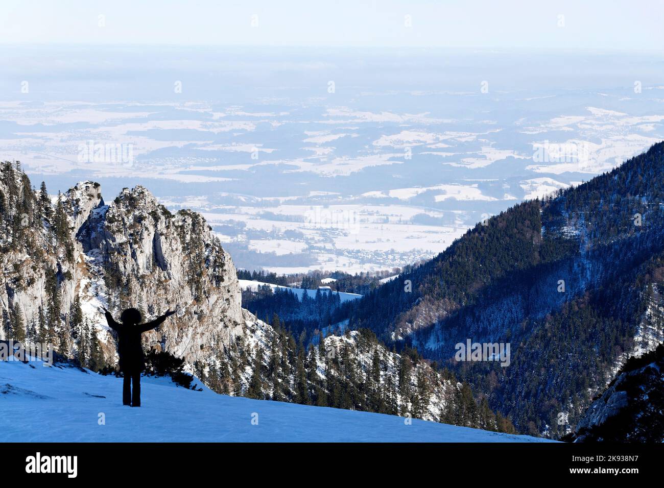 A person with open arms welcoming the winter alpine landscape, Kampenwand, Chiemgau,  Upper Bavaria, Germany Stock Photo