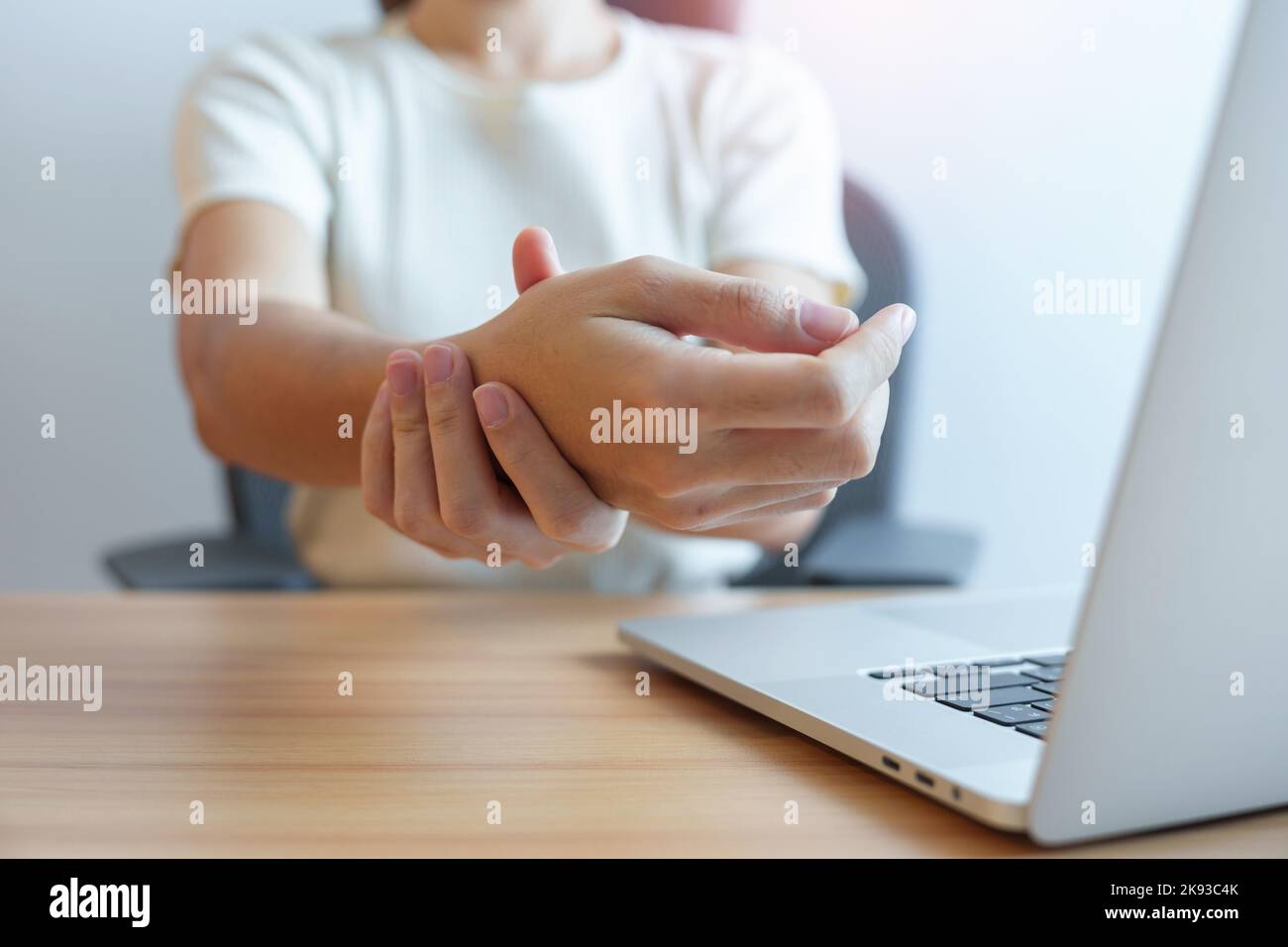 Woman having wrist pain when using laptop computer and mouse during