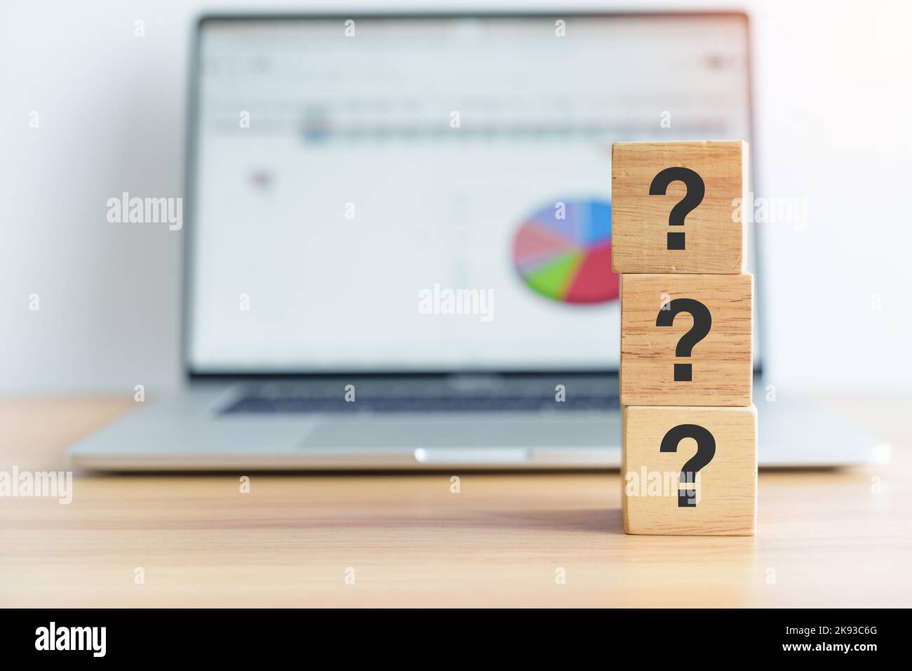 Questions Mark wood block and laptop computer with graph background