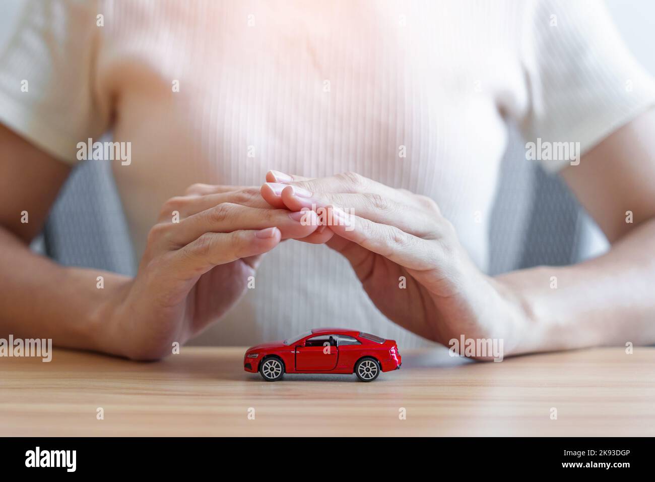 hand cover or protection red car toy on table. Car insurance, warranty, repair, Financial, maintenance  and rental concept Stock Photo