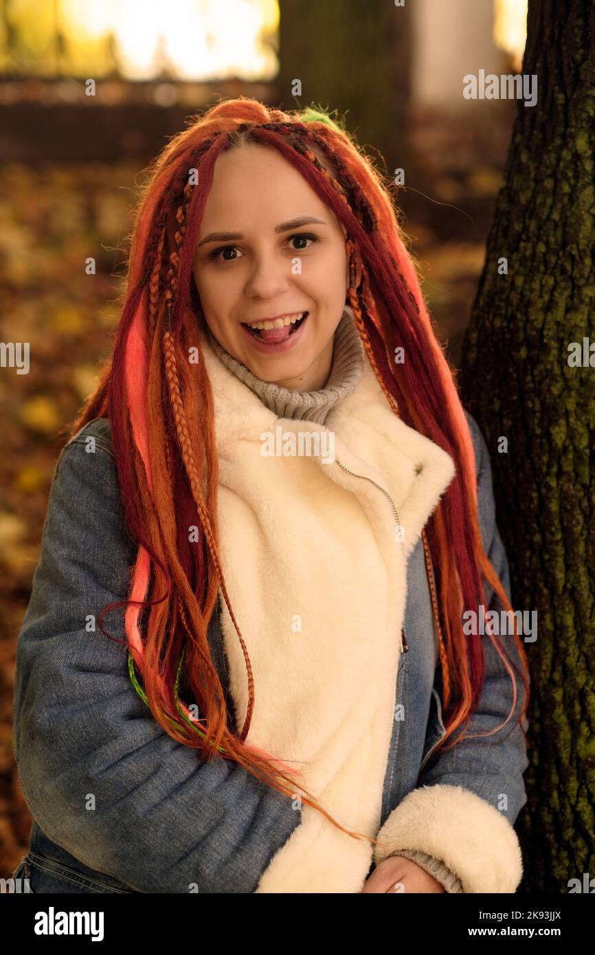 Portrait of young woman with ginger dreadlocks posing in forest park