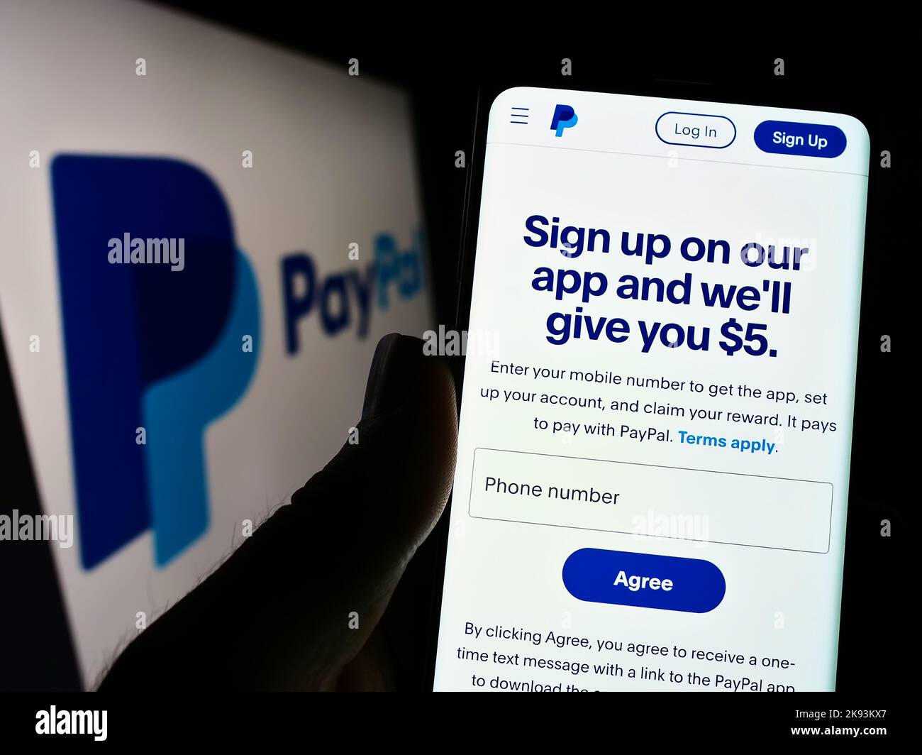 Person holding cellphone with webpage of US financial company PayPal Holdings Inc. on screen in front of logo. Focus on center of phone display. Stock Photo