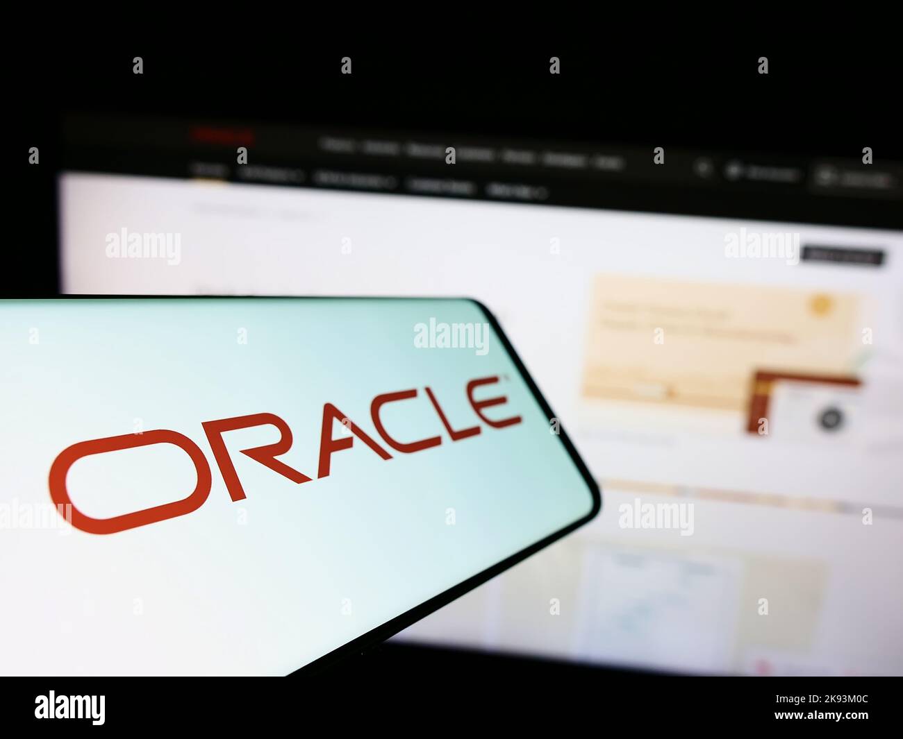 Mobile phone with logo of American technology company Oracle Corporation on screen in front of business website. Focus on left of phone display. Stock Photo