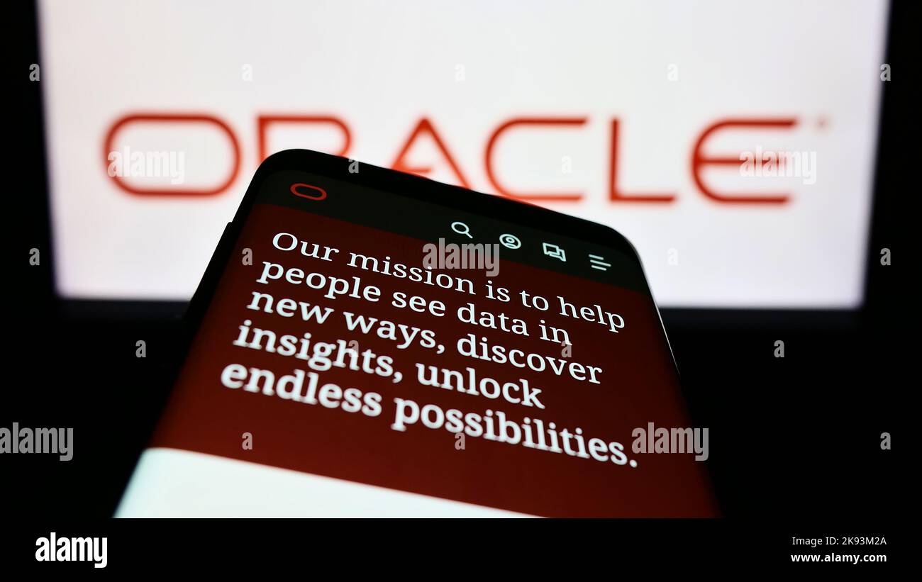 Smartphone with website of US technology company Oracle Corporation on screen in front of business logo. Focus on top-left of phone display. Stock Photo