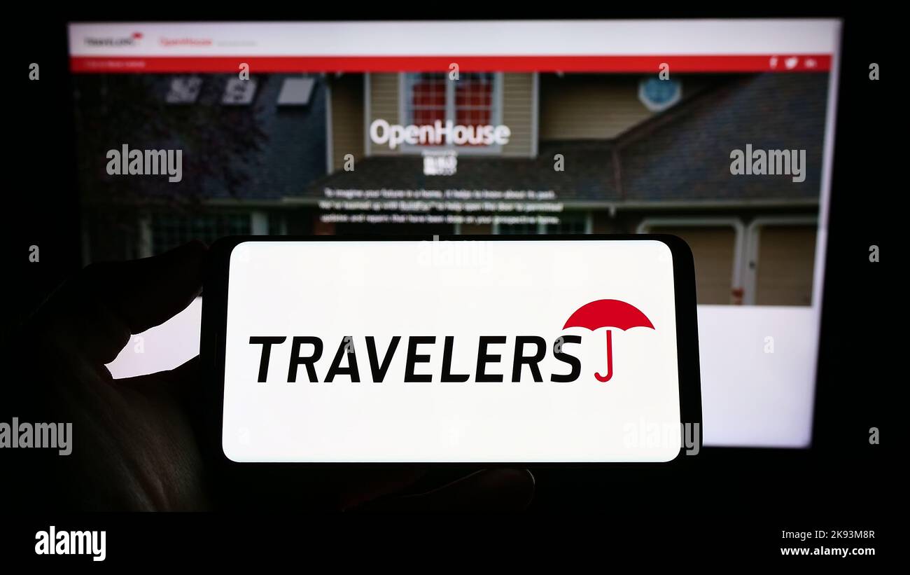 Person holding smartphone with logo of US insurance company The Travelers Companies Inc. on screen in front of website. Focus on phone display. Stock Photo