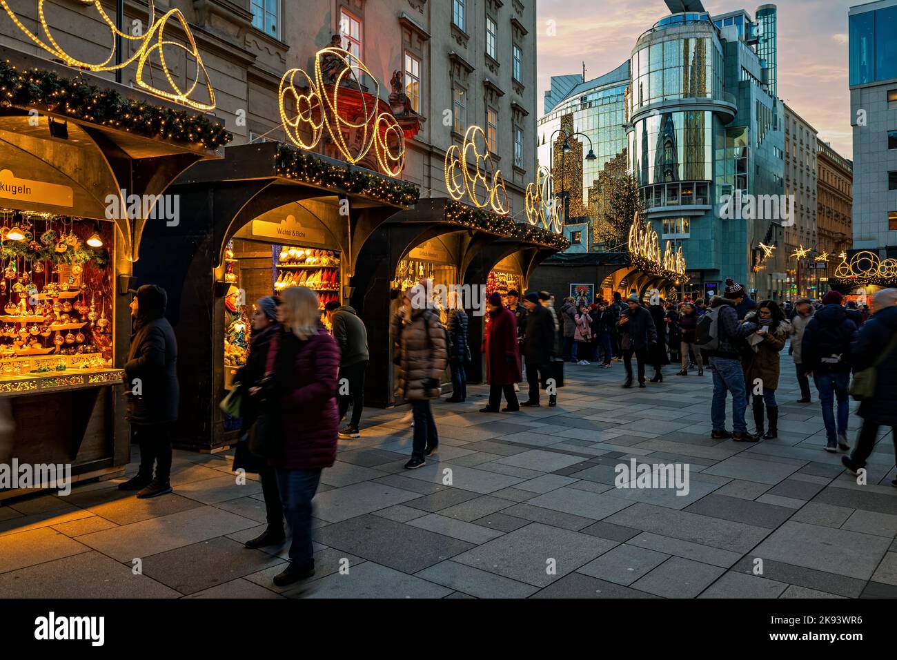 People walking along illuminated  kiosks at Christmas market in Vienna, Austria. Stock Photo