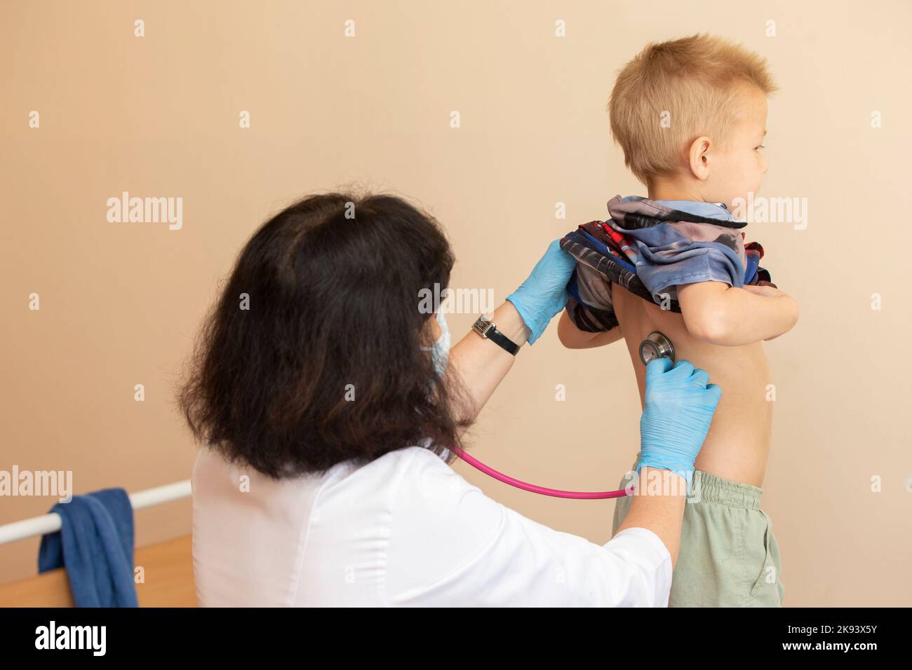 The doctor uses a stethoscope on the boy's back to check his health