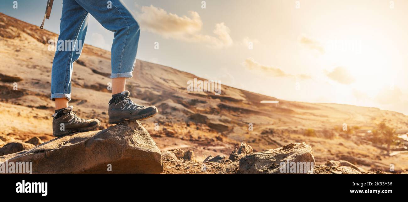 mountain trekking - woman hiker in hiking boots standing on rock. banner with copy space Stock Photo