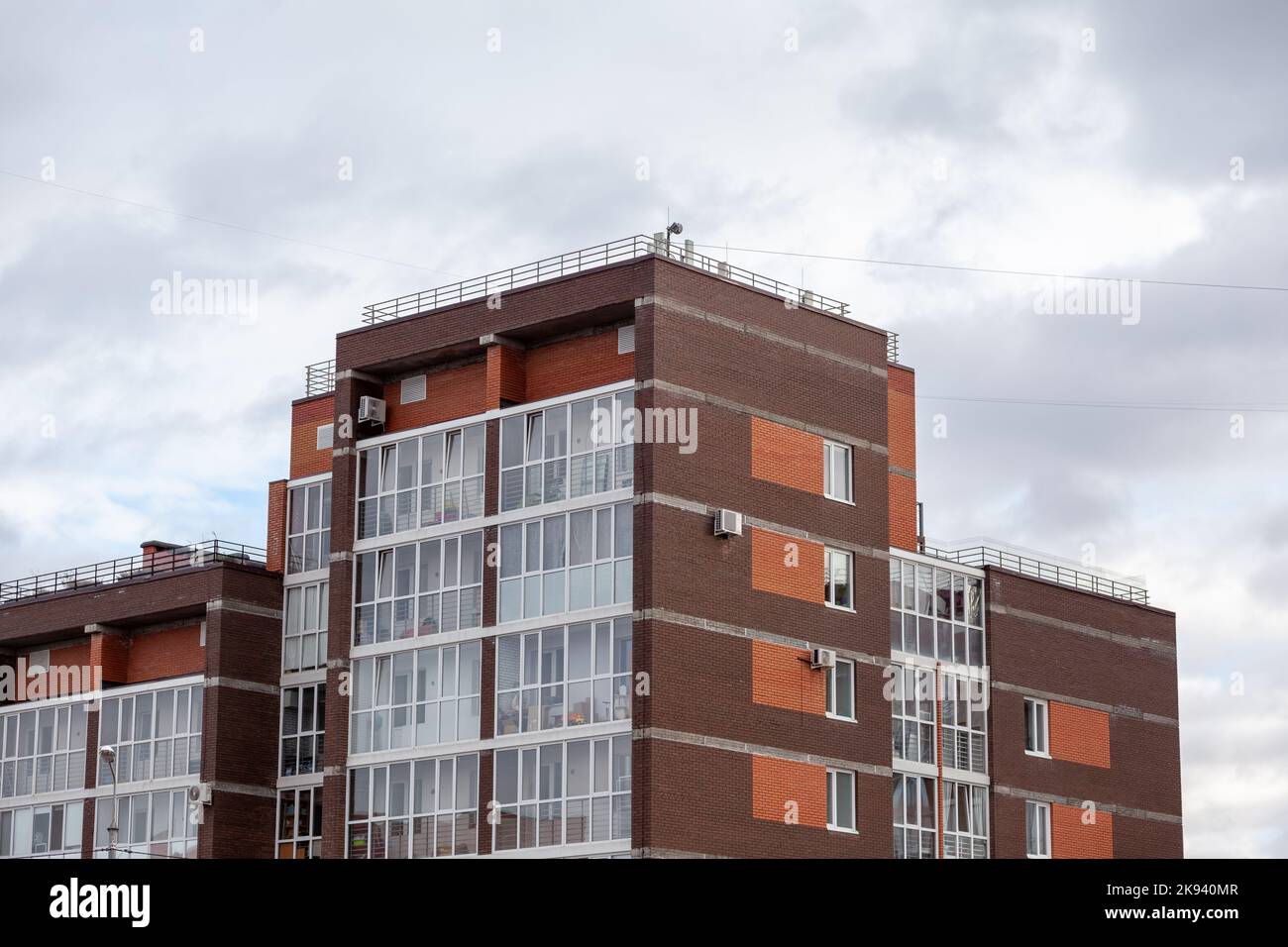 Windows of a residential multi-storey brick house. Modern buildings. The new multi-storey apartment brick building against the sky Stock Photo