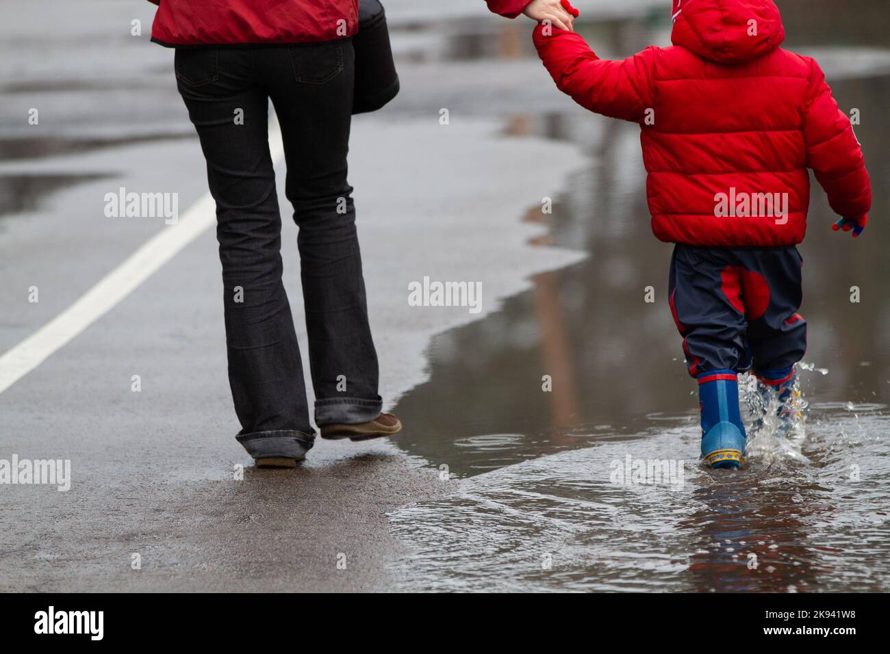 Mother and son in rubber boots after the rain, the focus is on the feet ...