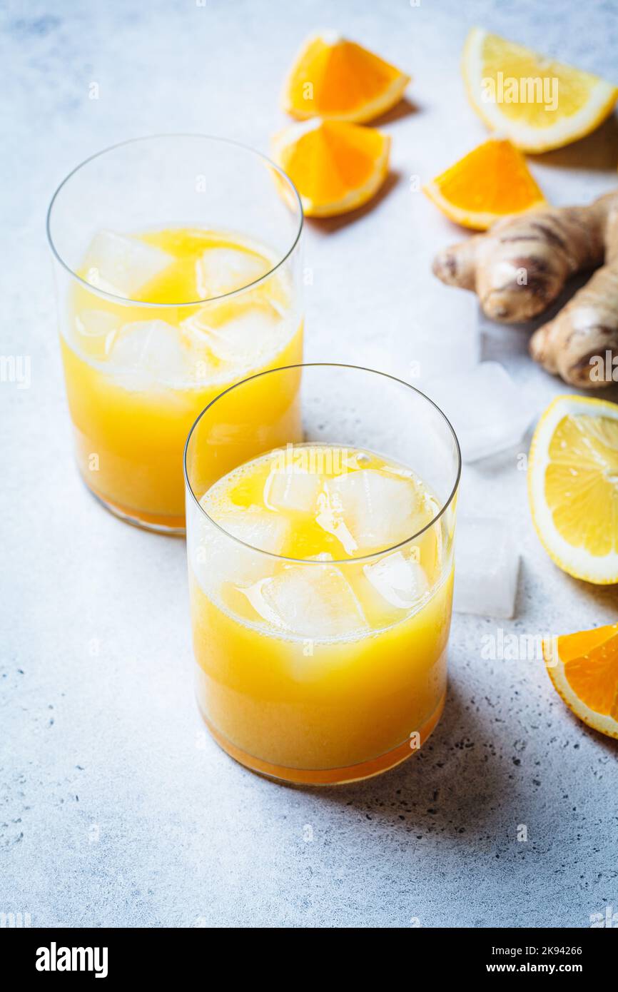 Orange lemon juice with ginger and spices in a glass, gray background. Immunity boosting drink, health concept, recipe for colds. Stock Photo