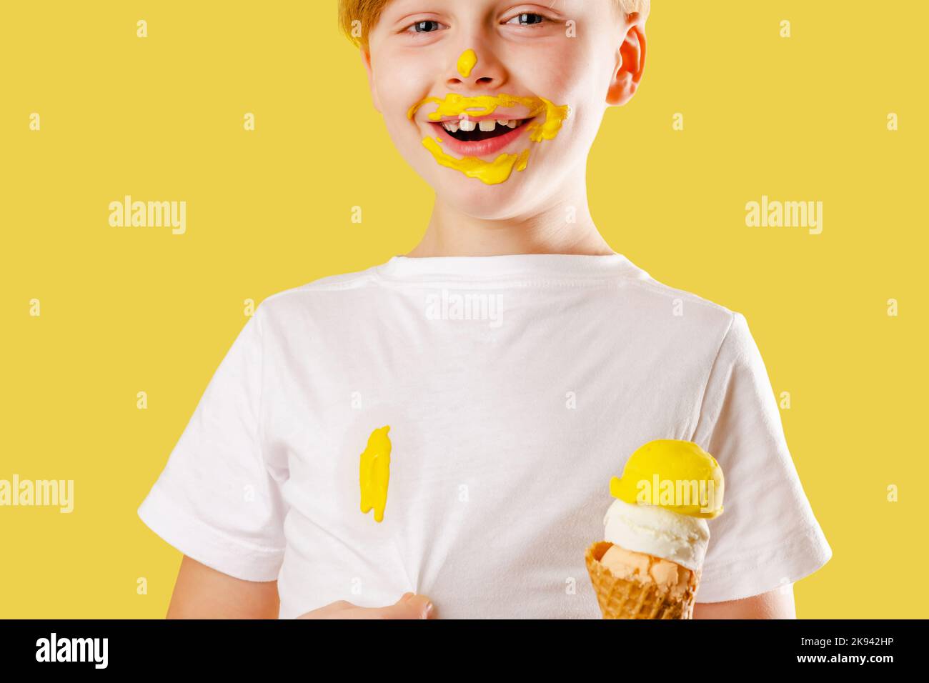 A cheerful boy showing and looking at the camera an ice cream stain on