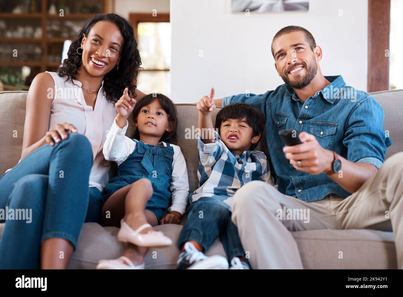 Go back to the cartoons, dad. a couple watching something on the television with their two young kids. Stock Photo