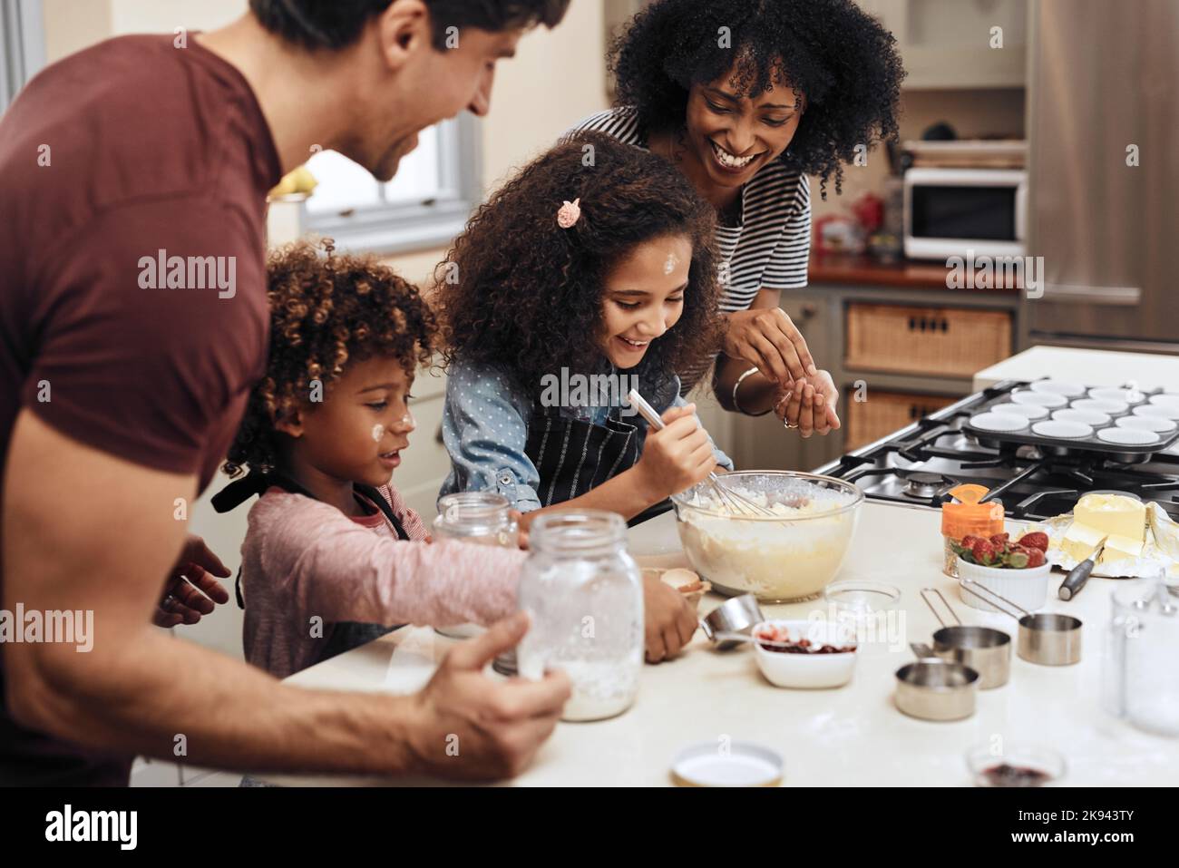 Were having so much fun with baking. a young couple baking at home with their two children. Stock Photo
