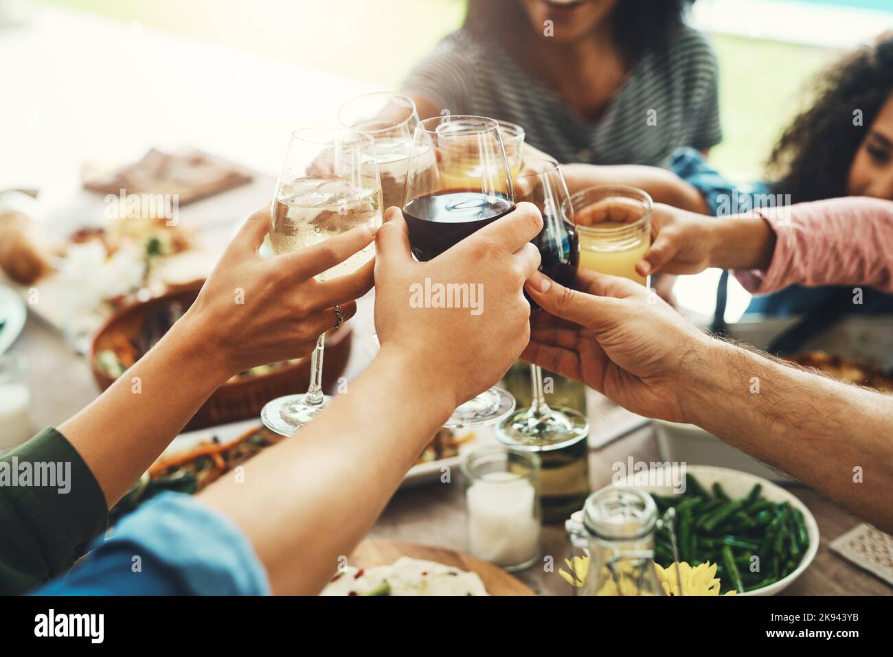 Drinks up everybody. a group of unrecognizable people joining their glasses together for a toast while enjoying a meal together outdoors. Stock Photo