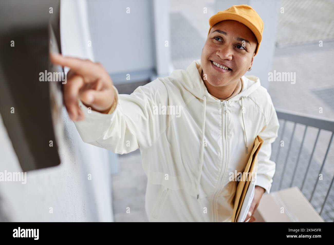 High angle portrait of smiling woman delivering packages and ringing doorbell Stock Photo