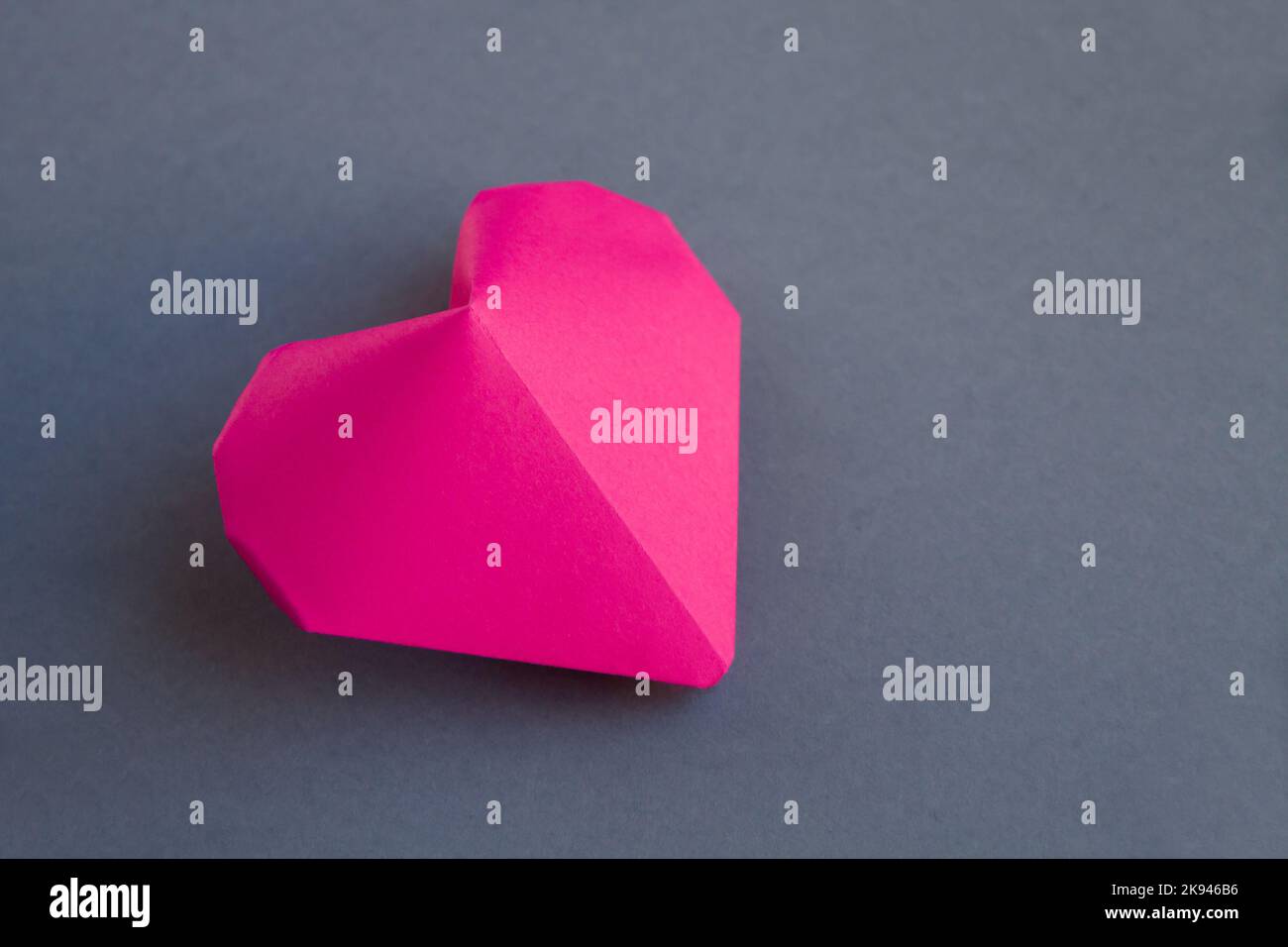 Pink paper heart origami isolated on a blank grey background ...