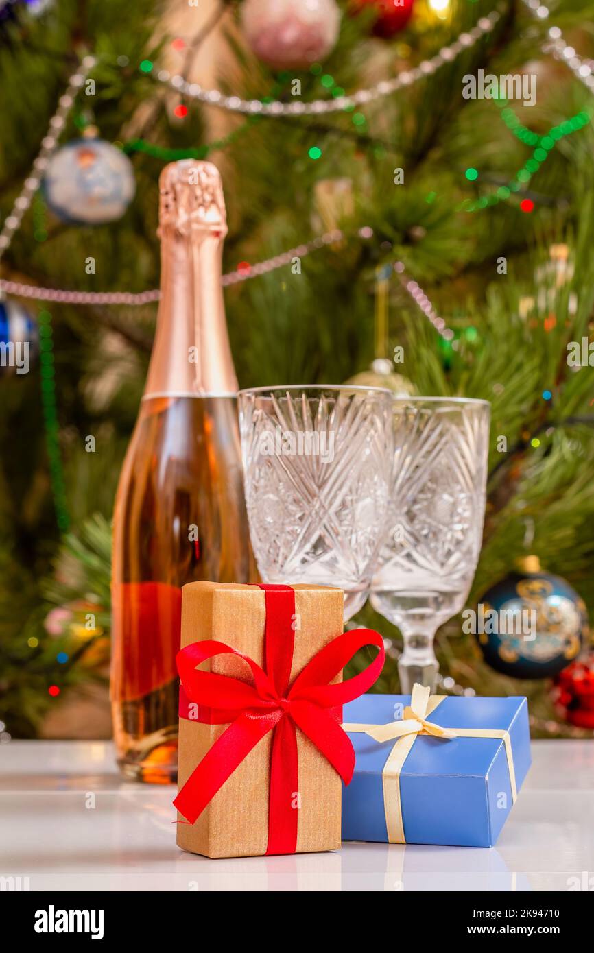 https://c8.alamy.com/comp/2K94710/gift-boxes-and-blurred-crystal-glasses-bottle-of-champagne-and-christmas-tree-with-twinkling-party-lights-and-toy-balls-2K94710.jpg