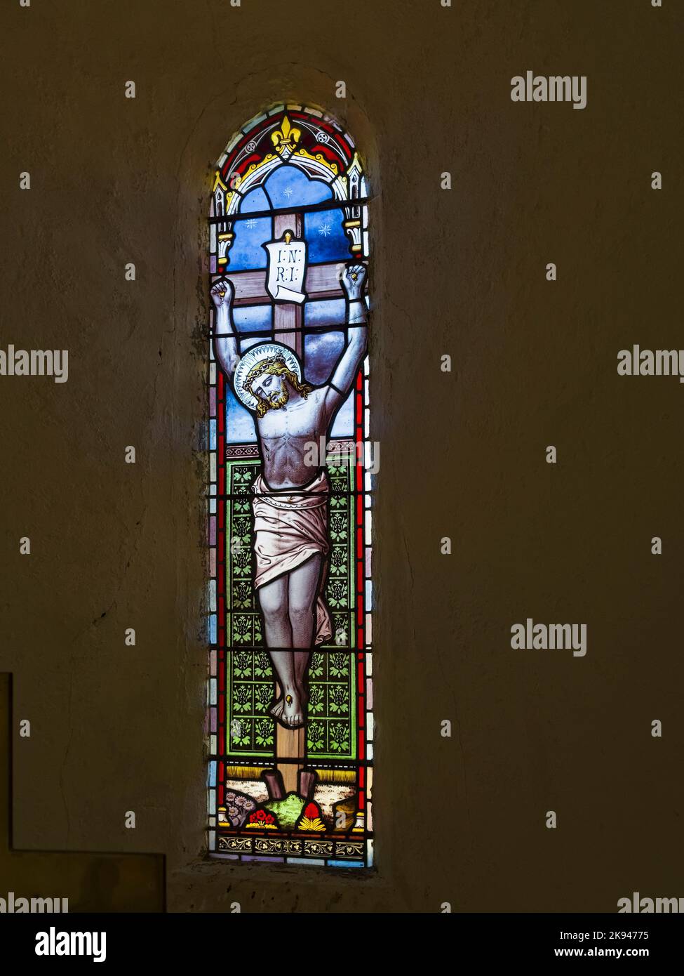 Stained glass window in St Aidans Church, Throckrington, Northumberland, UK depicting Christ on the cross. Stock Photo