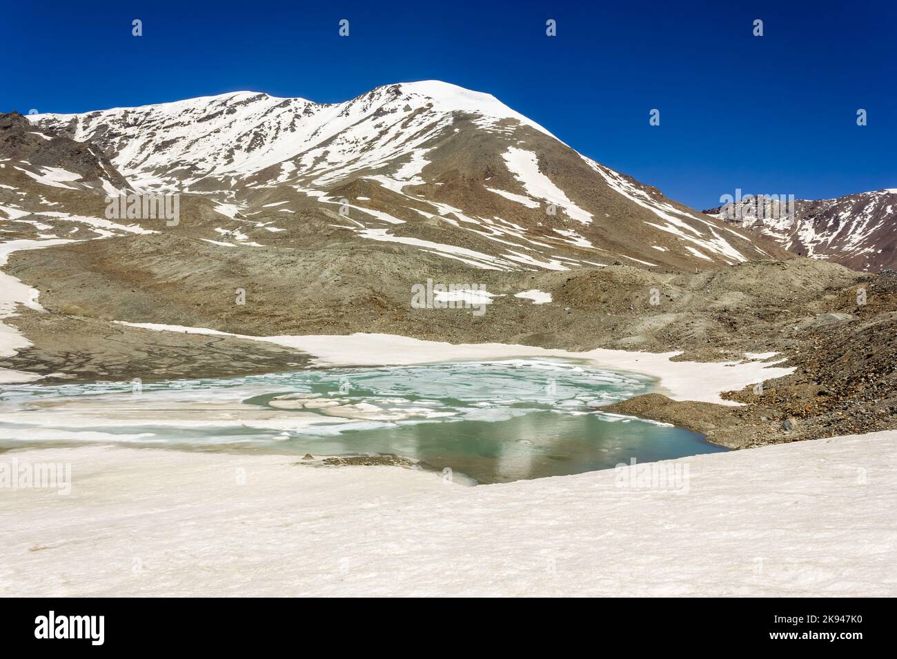 The partially frozen lake on top of the high altitude pass of Shingo La in the Great Himalayan range on the trek from Lahaul to Zanskar in North India Stock Photo