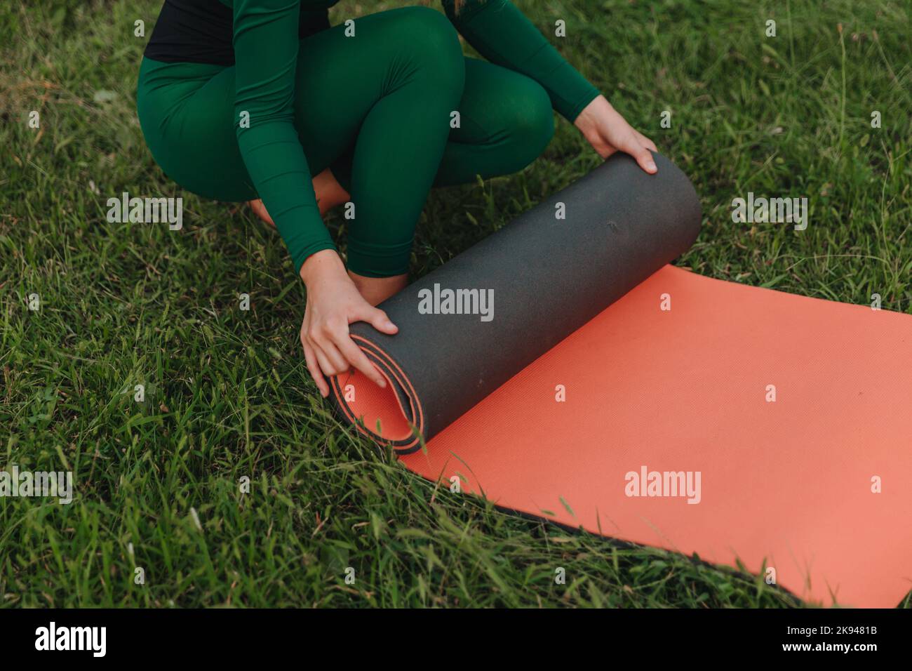 A young beautiful girl is doing yoga in a calm warm evening on the grass. Stock Photo