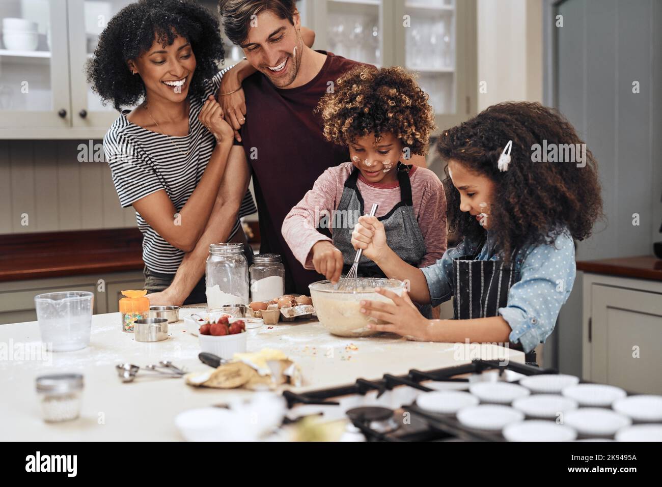 They caught on really fast. a young couple baking at home with their two children. Stock Photo
