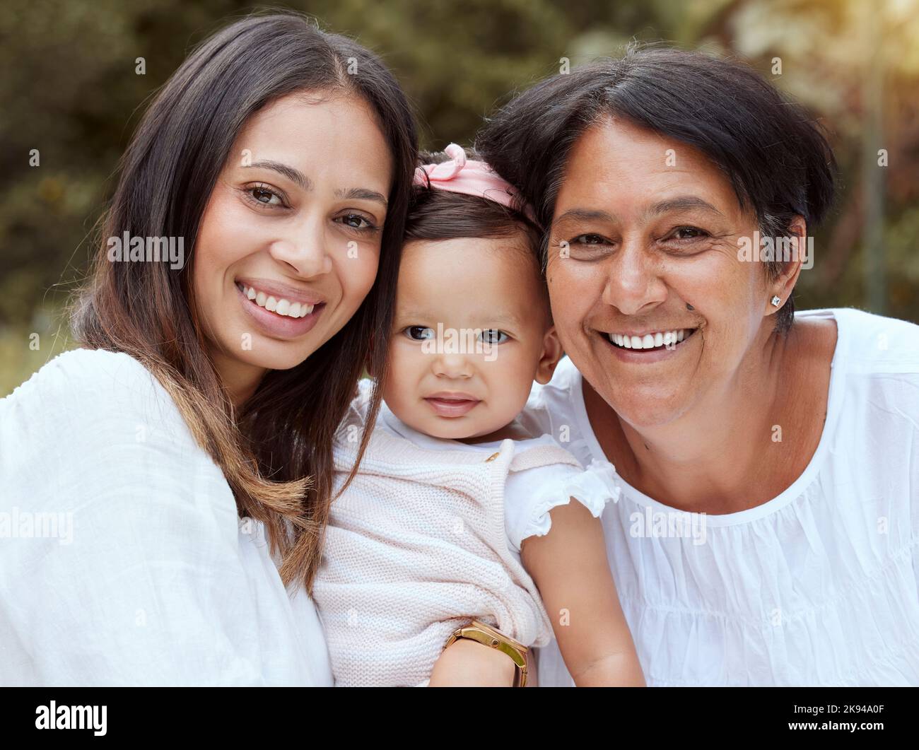 Mother, baby and family bonding outdoor with a smile, love and care in a nature park. Portrait of women generations, mama and elderly woman holding a Stock Photo
