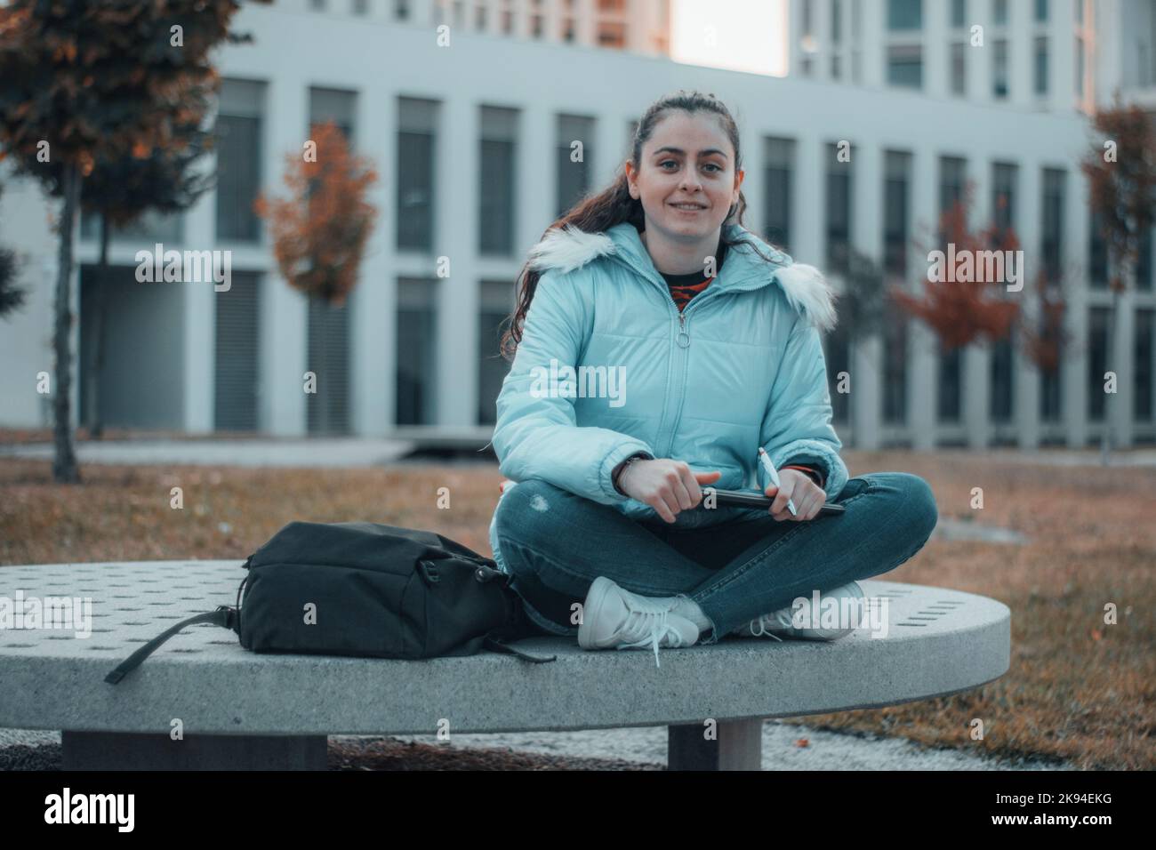 A Spanish woman sitting on a bench while writing on her clipboard