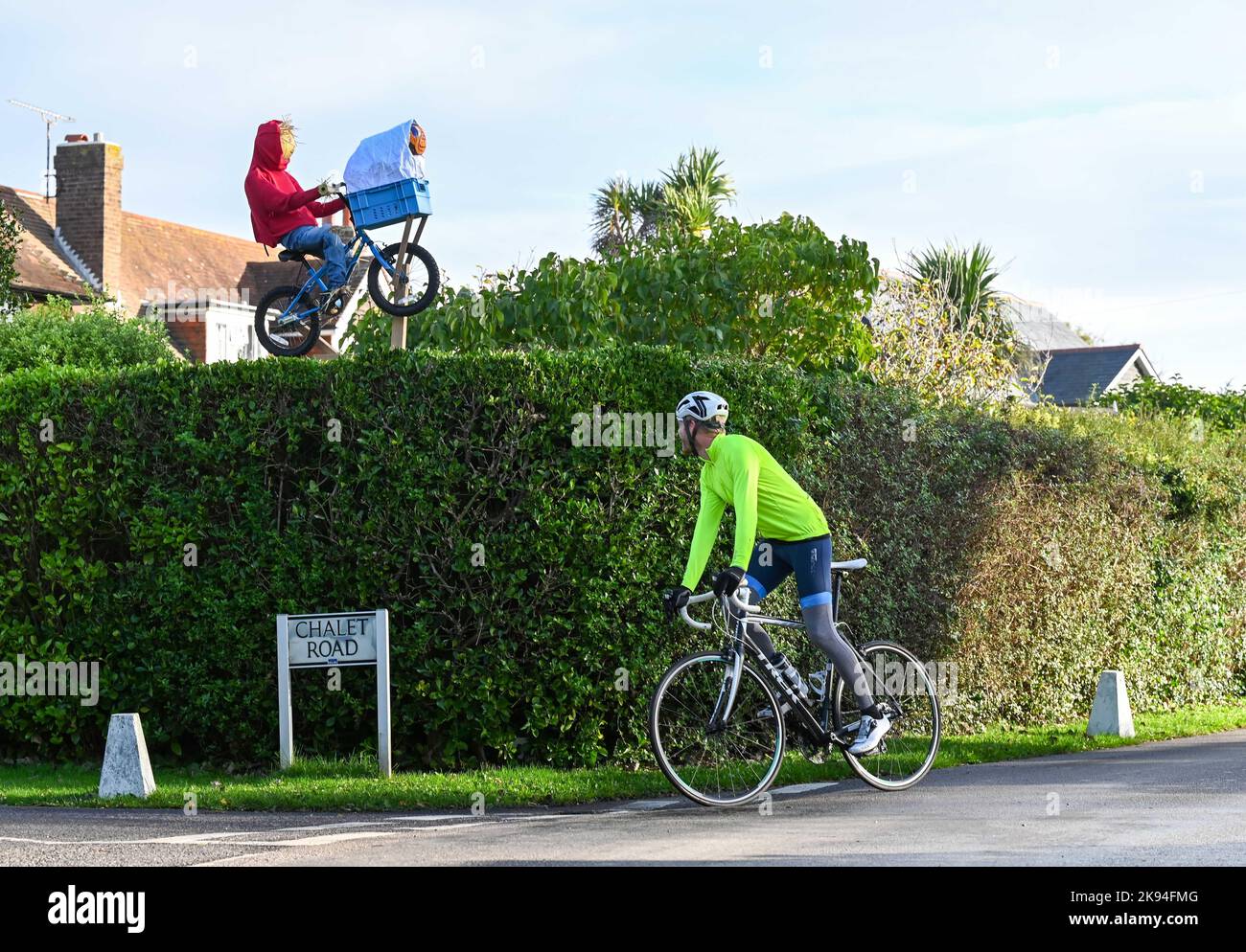 Worthing UK 26th October 2022 - A cyclist passes by the ET scarecrow which has appeared flying over a hedge in the annual Scarecrow Festival in Ferring village near Worthing , West Sussex . Over 70 scarecrows are expected to appear throughout the village over the week : Credit Simon Dack / Alamy Live News Stock Photo