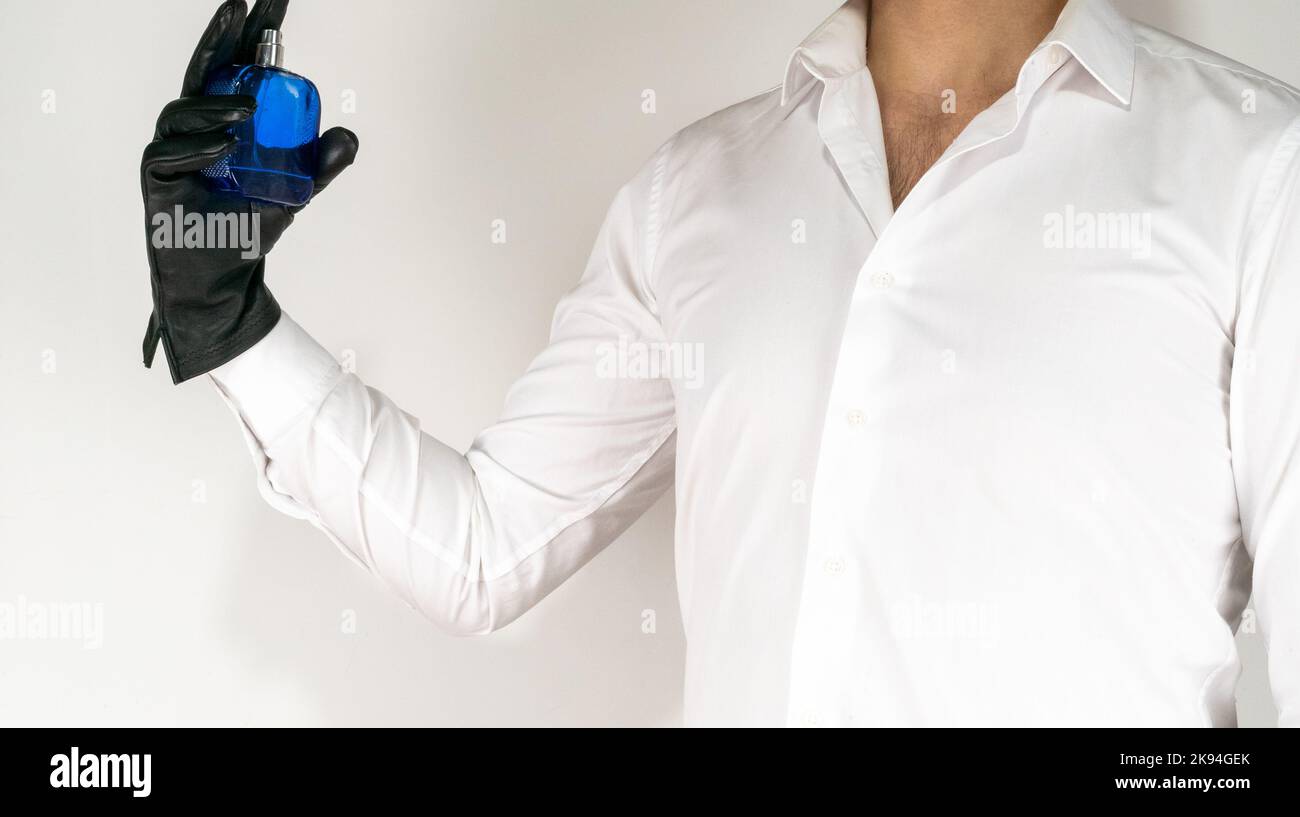 White shirt man spray perfume with hand. Blue bottle and leather black gloves on white