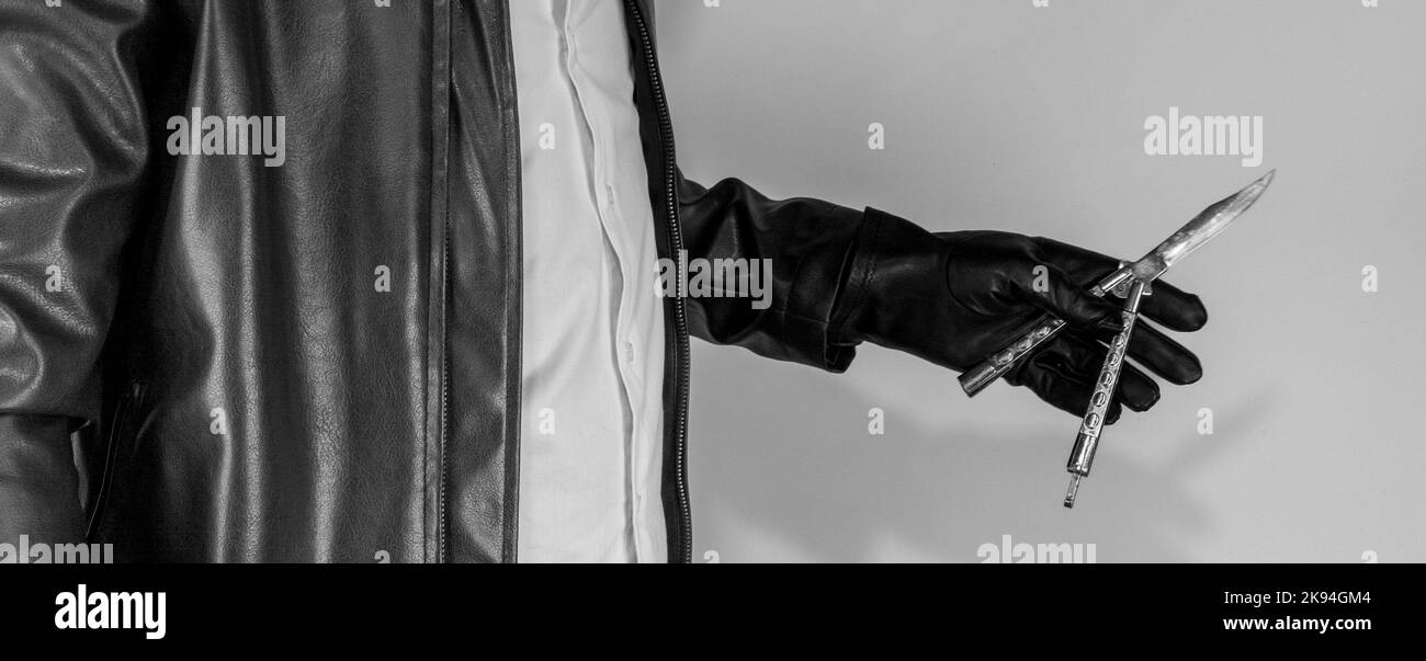 Mafia men holding butterfly knife. Spy, killer or assassin men holding butterfly knife with his black leather gloves. Black and white also grain textu Stock Photo