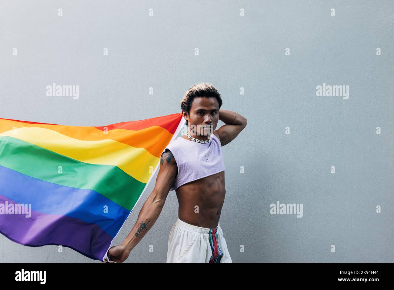 Young man holding rainbow flag hi-res stock photography and images - Alamy