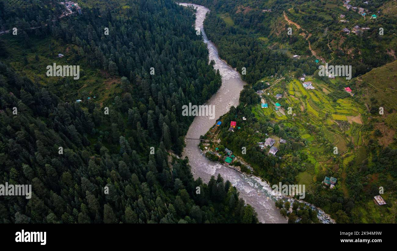 An aerial view of a river flowing through green forests and rural ...