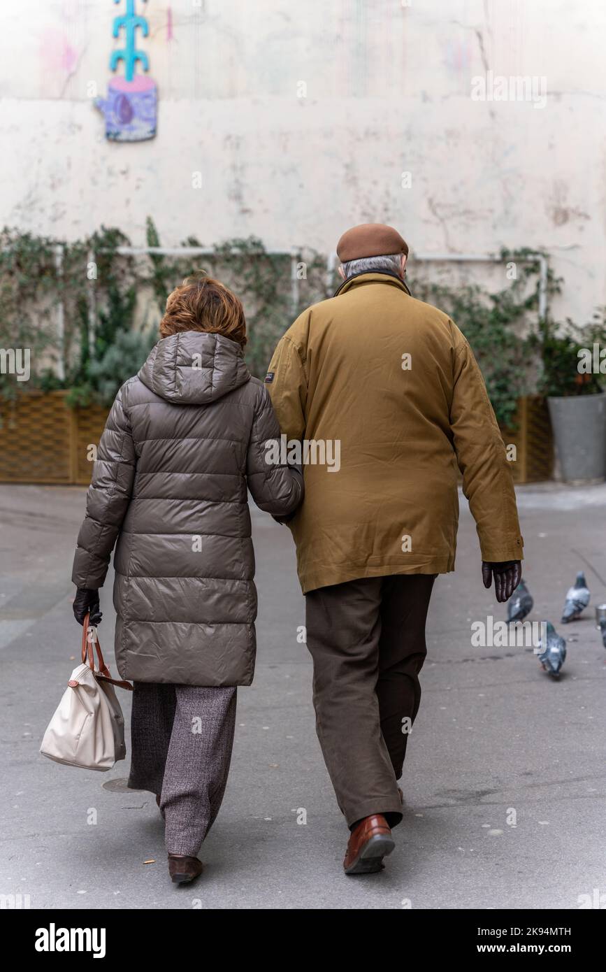 An elderly couple walks down a street while holding hands Stock Photo ...