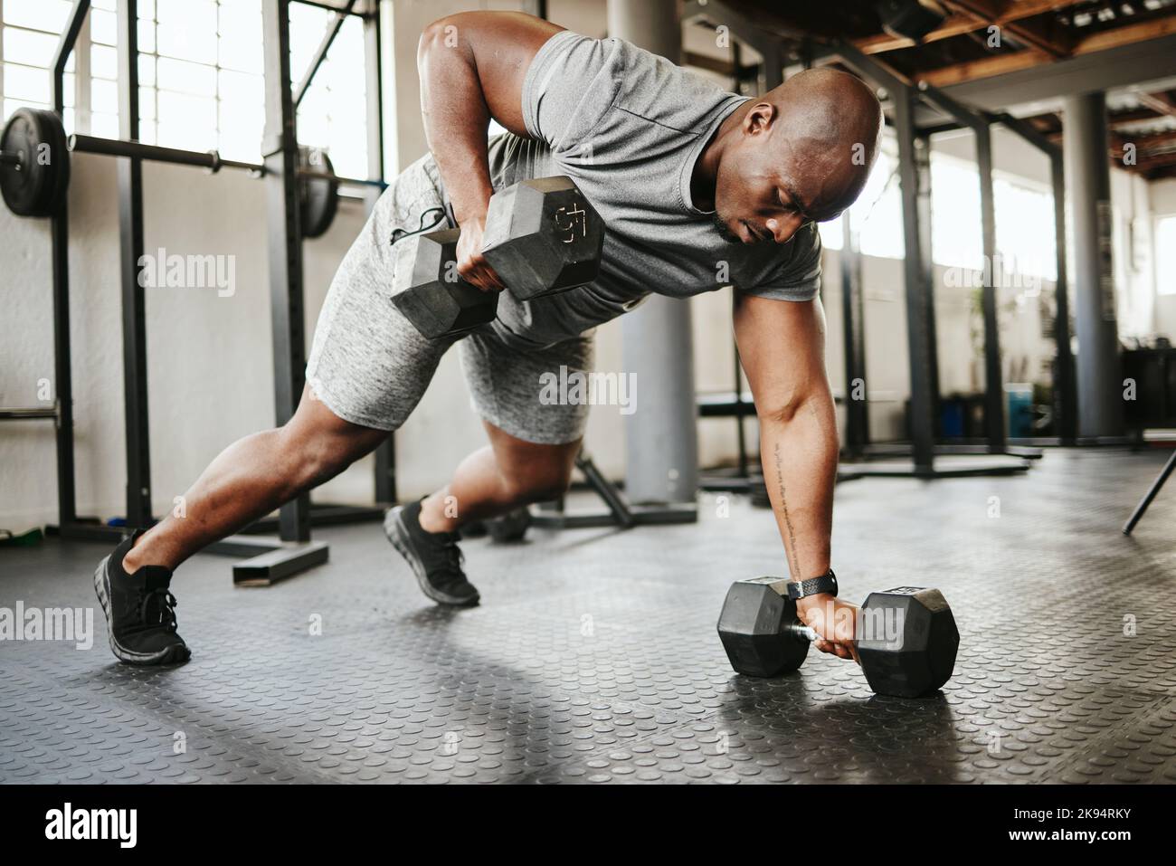 Dumbbell, fitness and bodybuilder black man with workout training in gym or garage studio for wellness, body goal and motivation. Power, strong and Stock Photo