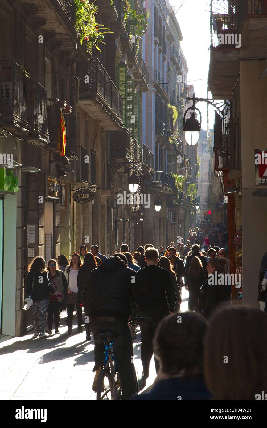 A vertical shot of people walking down backlit street in Barcelona ...