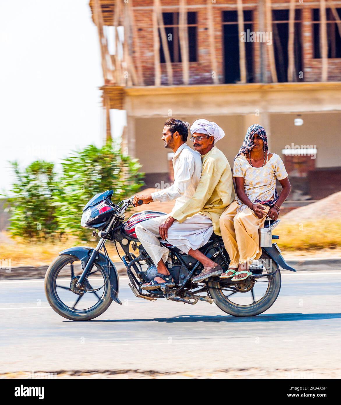 RAJASTHAN - INDIA - OCT 18, 2012: Mother, father and small child riding on scooter through busy highway street  in Rajasthan, India. Up to six family Stock Photo