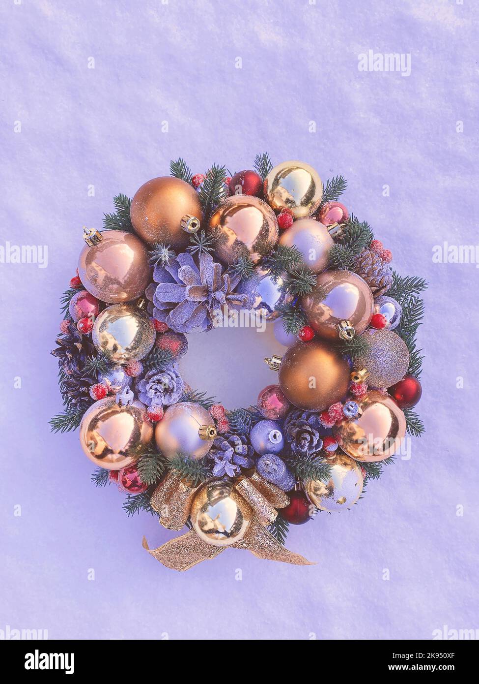 Christmas decorative wreath with pine cones, Christmas tree golden balls and ornaments on a textured background. Toned image in color Very peri Stock Photo