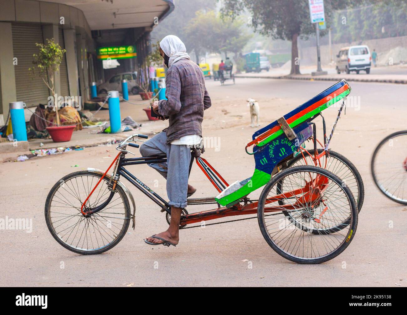 DELHI, INDIA - NOV 10: Rickshaw rider waits for passengers early ...