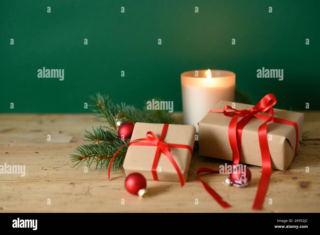 Two Christmas gift boxes with red ribbons, and candlelight on a wooden ...