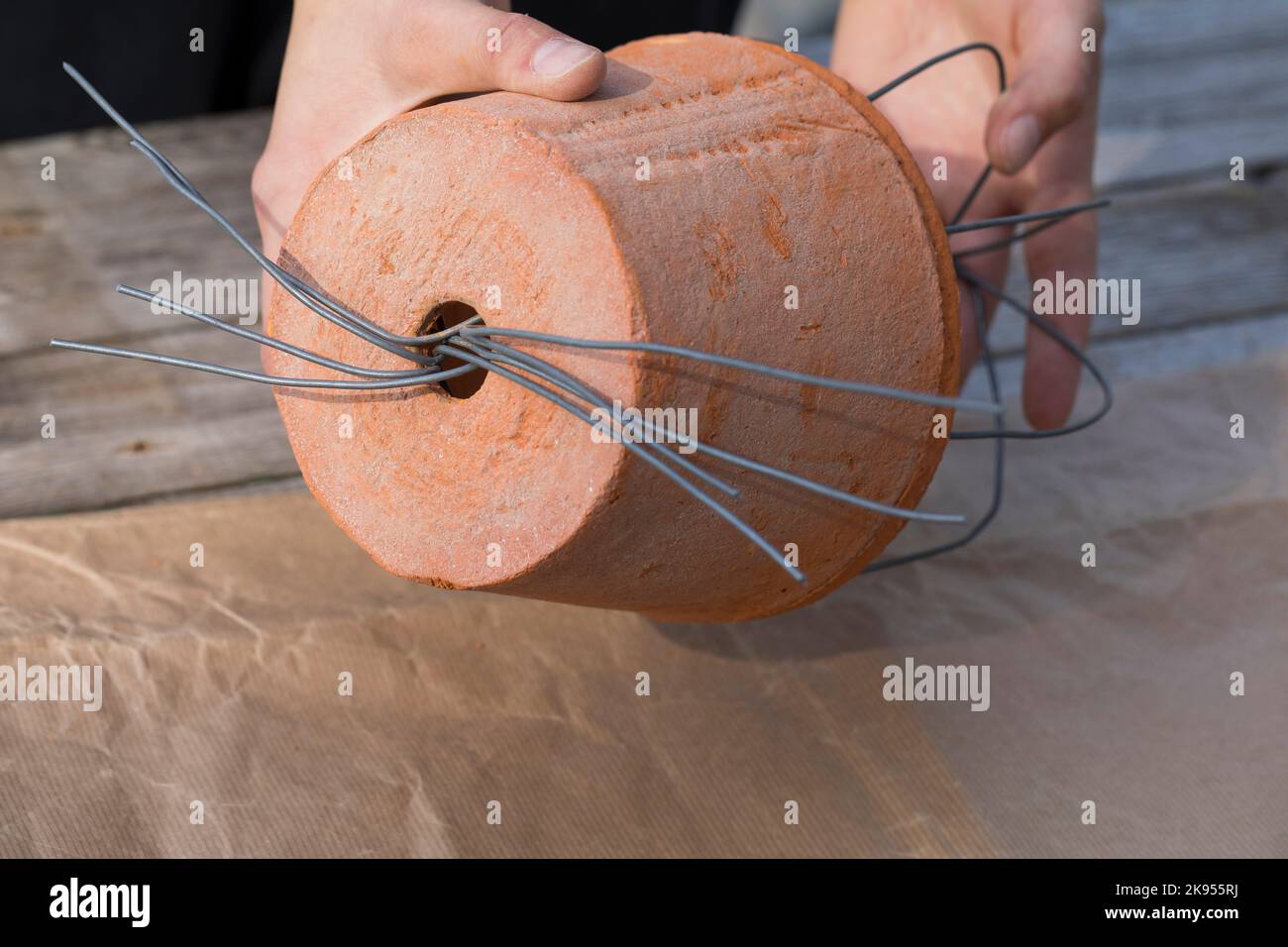 making a dispenser for nesting material for birds or squirrels, step 3: the free end of the wire are bent around a flowerpot, series picture 3/5 Stock Photo