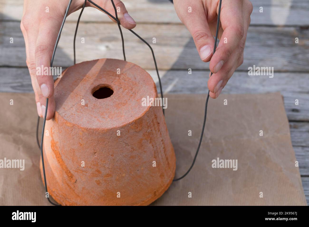 making a dispenser for nesting material for birds or squirrels, step 3: the free end of the wire are bent around a flowerpot, series picture 3/5 Stock Photo