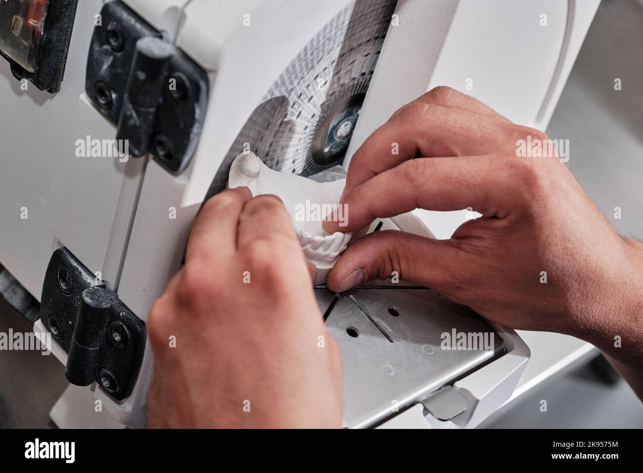Dental technician trimming excess material from plaster models. Dental