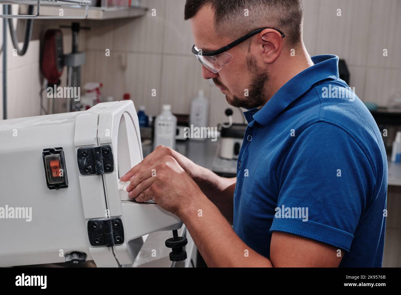 Dental technician trimming excess material from plaster models. Dental