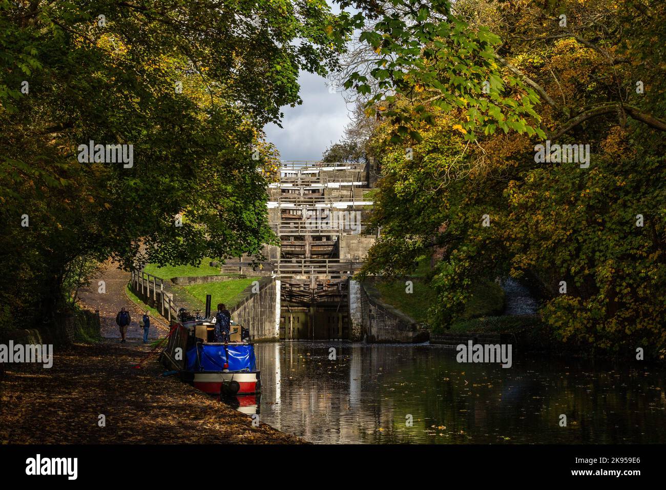 A barge (narrowboat) is moored up at the side of the Leeds Liverpool canal below Five Rise Locks (Staircase lock)  in Bingley, West Yorkshire. Stock Photo